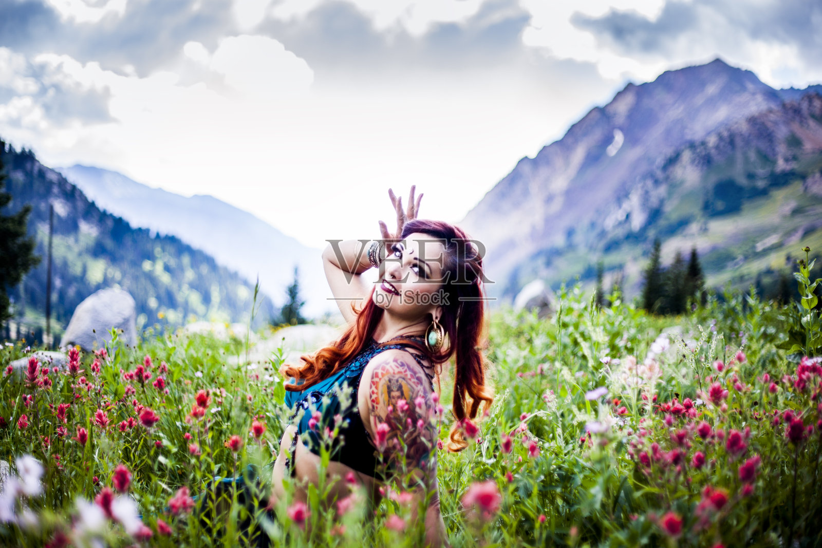 美丽的肚皮舞演员坐在一片花丛中照片摄影图片