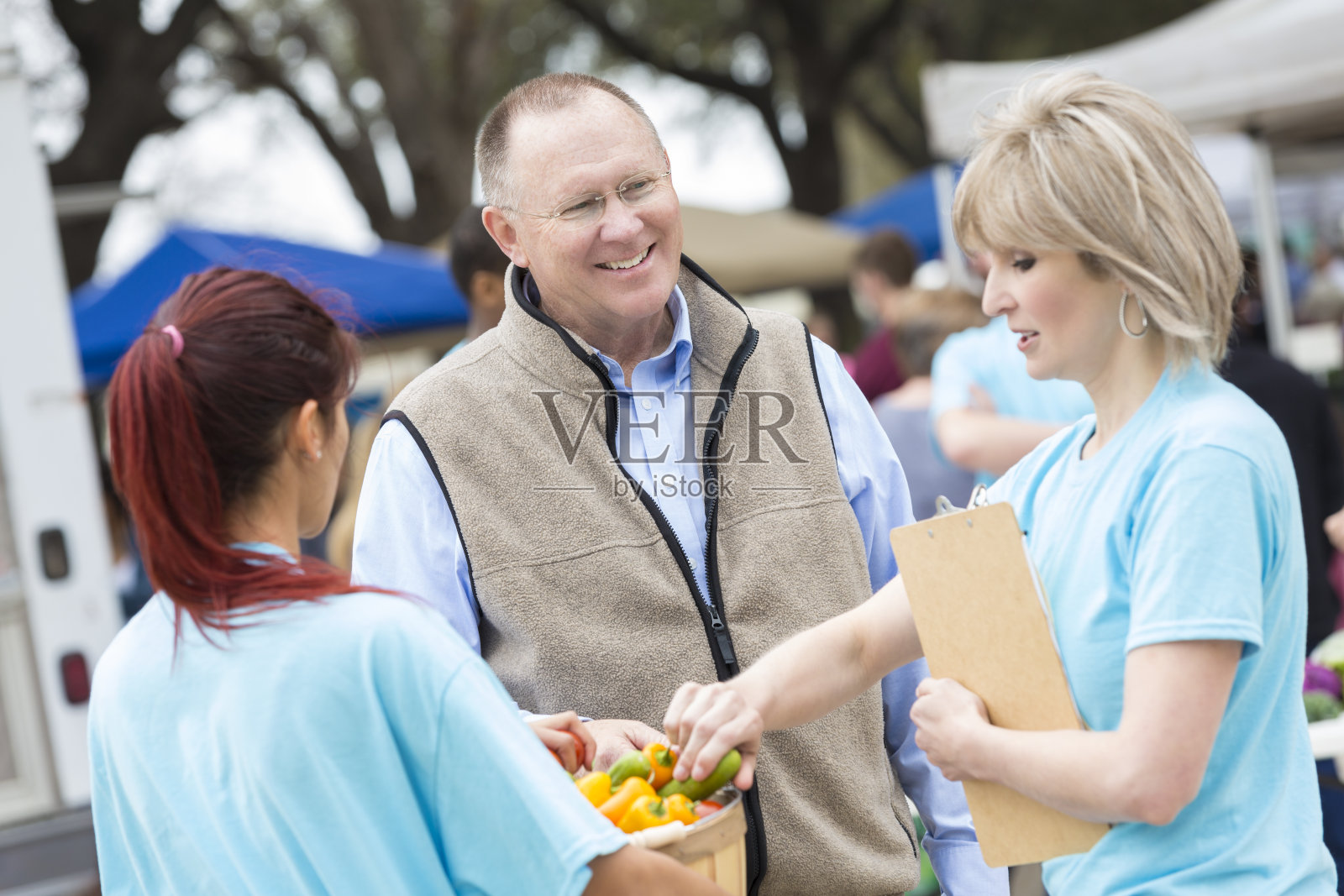 高级农贸市场经理陪同卖主检查农产品照片摄影图片