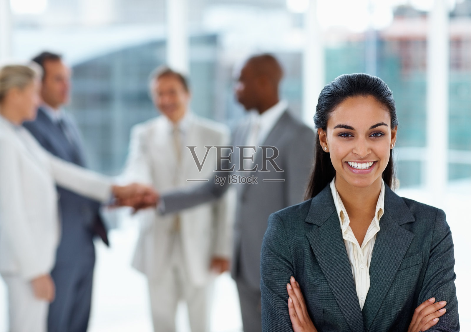 年轻的女商人面带微笑，身后是同事照片摄影图片