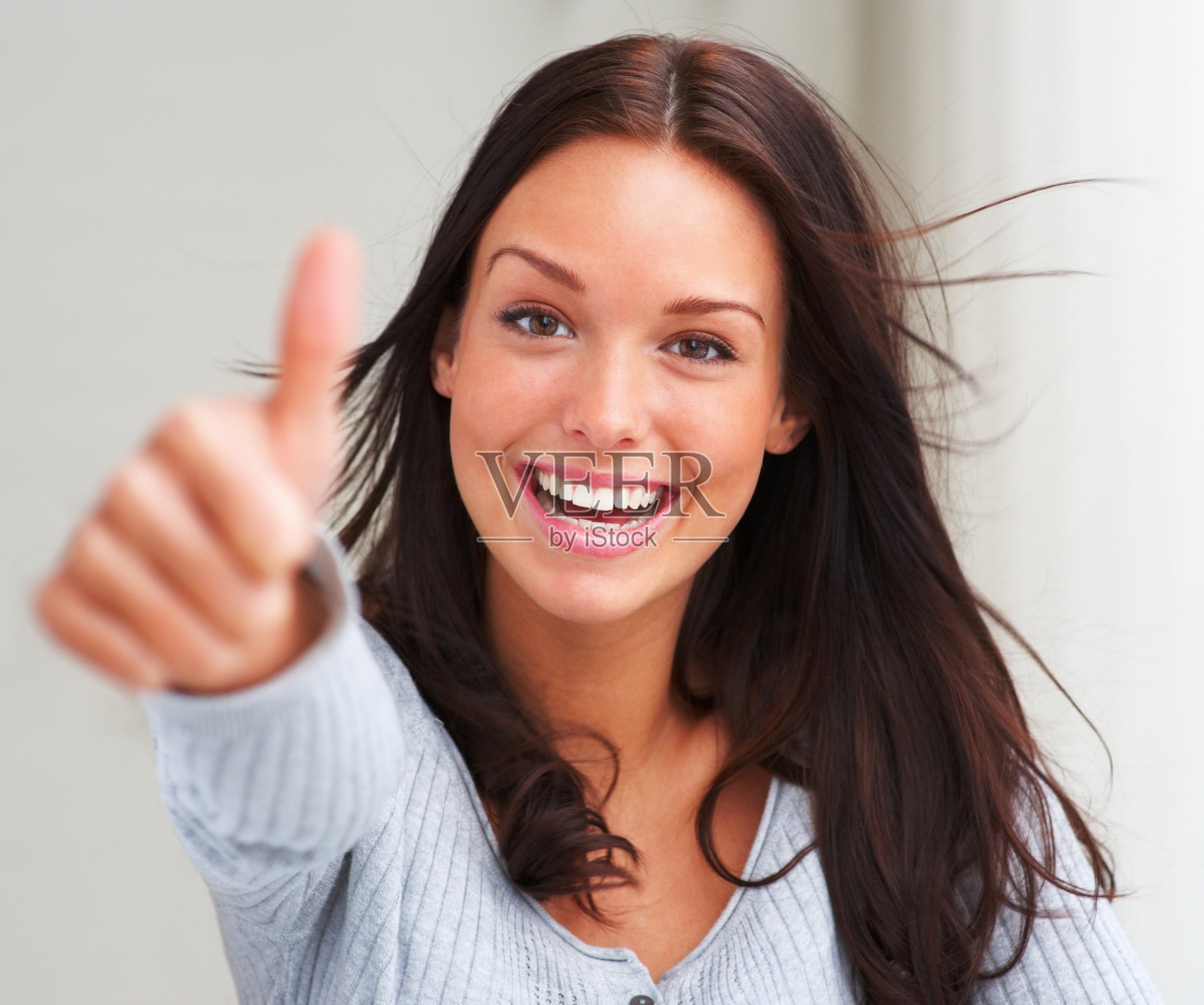 一个快乐的年轻女人的特写显示大拇指向上的标志照片摄影图片