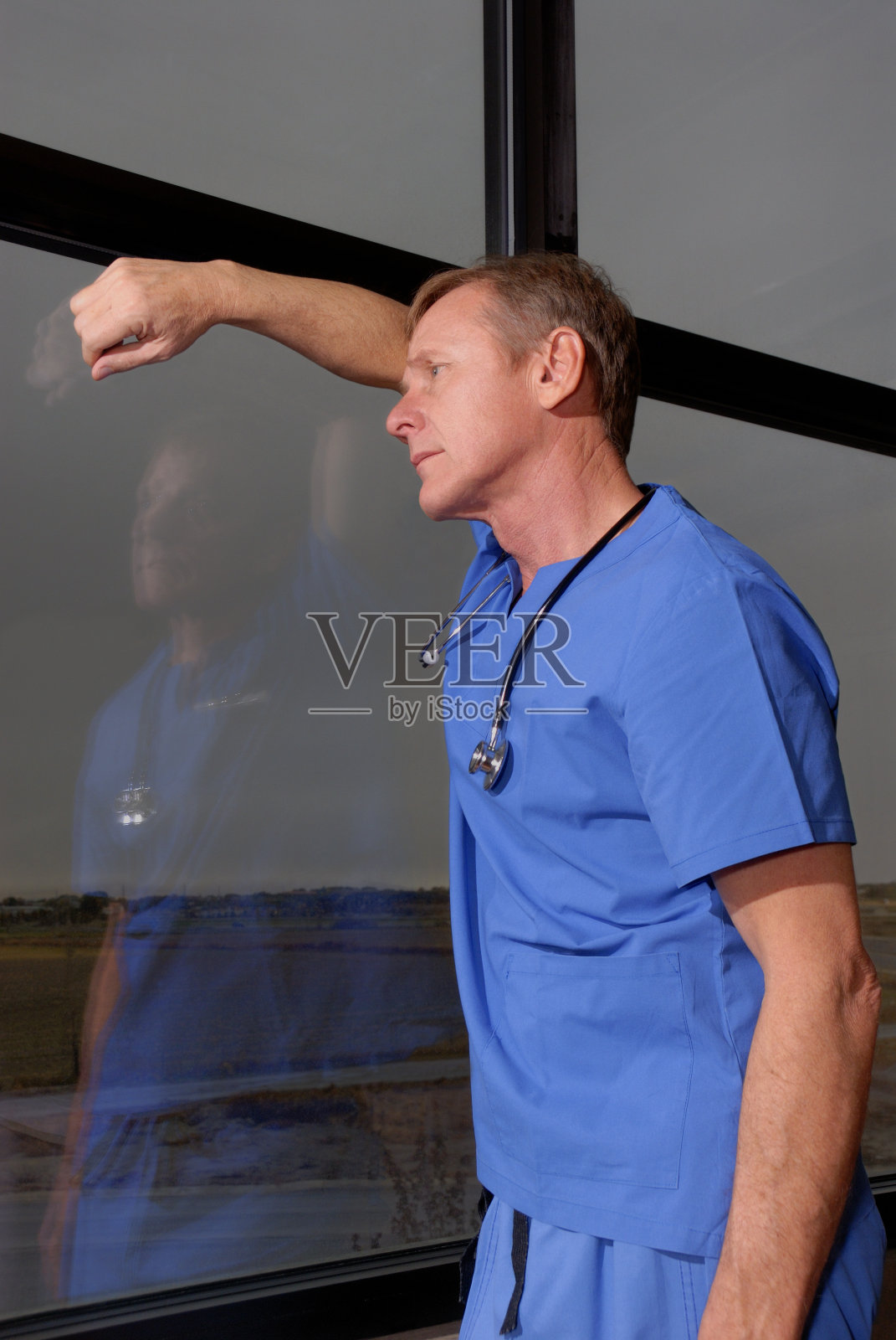 疲惫的医生望着雨夜的窗外照片摄影图片