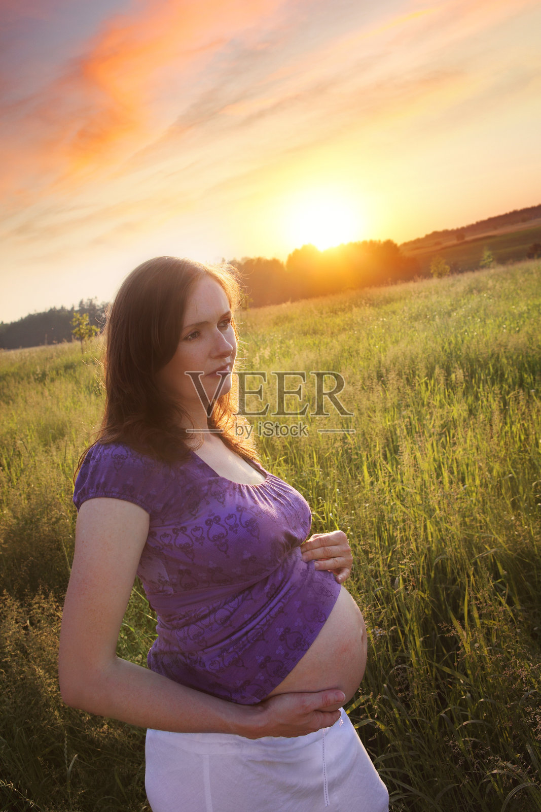 夕阳下草地上的孕妇照片摄影图片