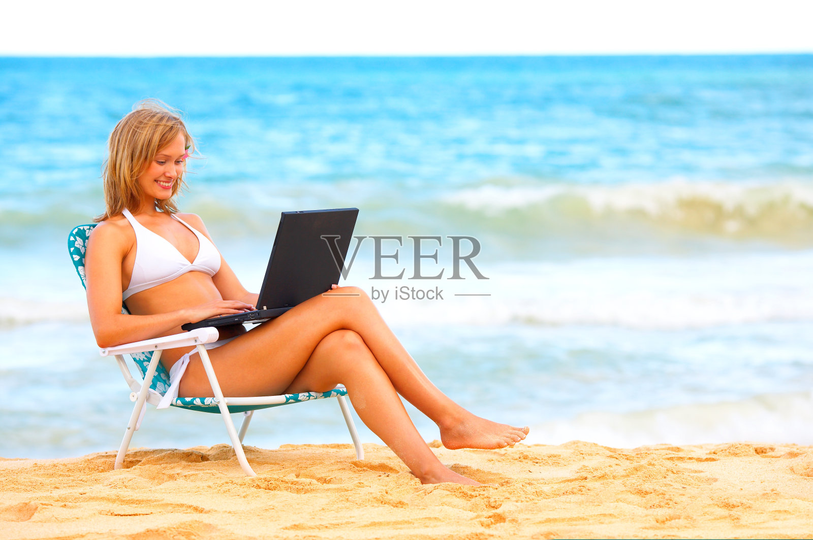 沙滩上的美丽年轻女子，手提电脑照片摄影图片