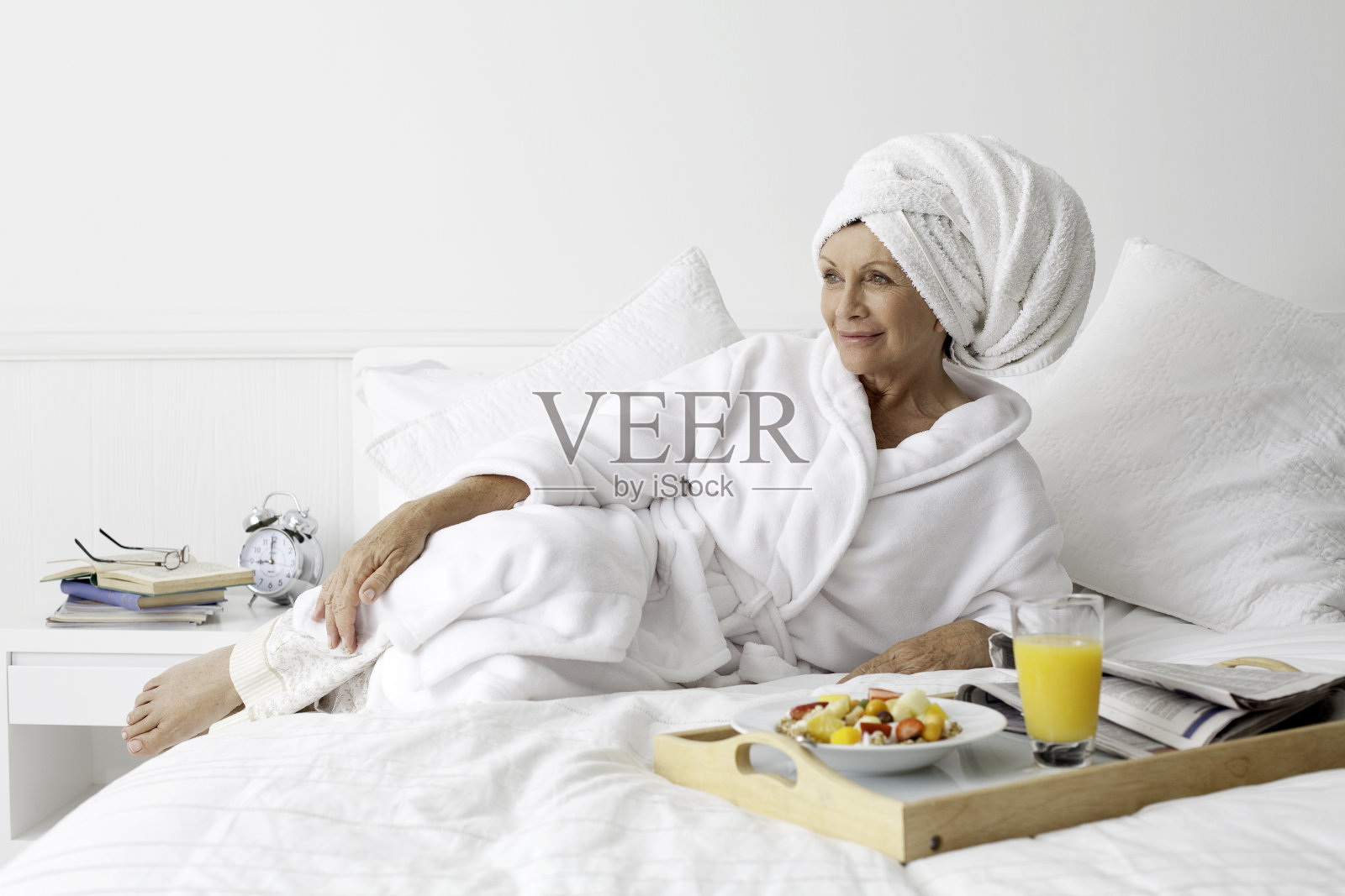 快乐的老女人在床上吃早餐。照片摄影图片