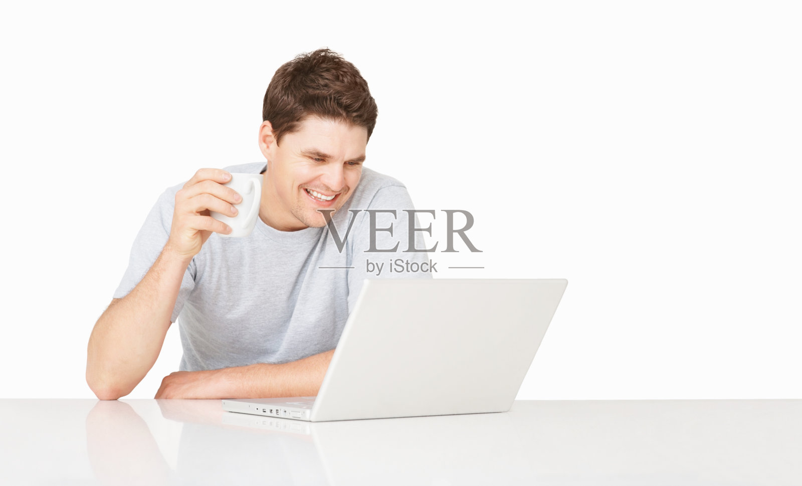 一边喝咖啡一边使用笔记本电脑的快乐男人照片摄影图片
