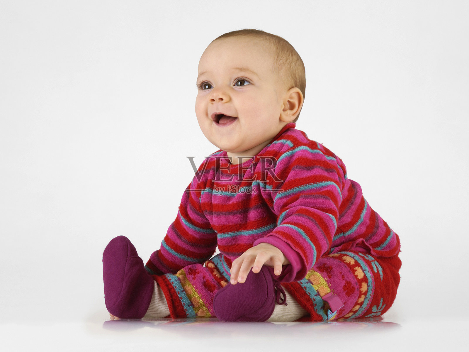 宝宝穿着五颜六色的衣服微笑着，坐在白色的背景上照片摄影图片