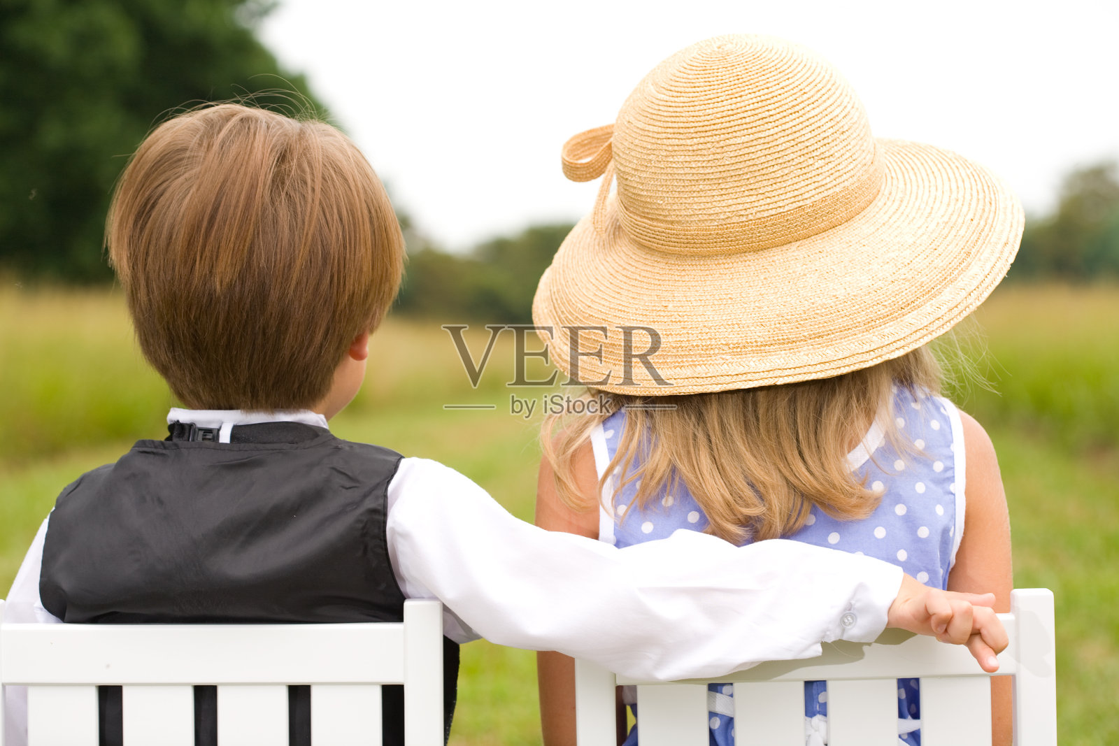 男孩的后视图与女孩的椅背上的手臂照片摄影图片