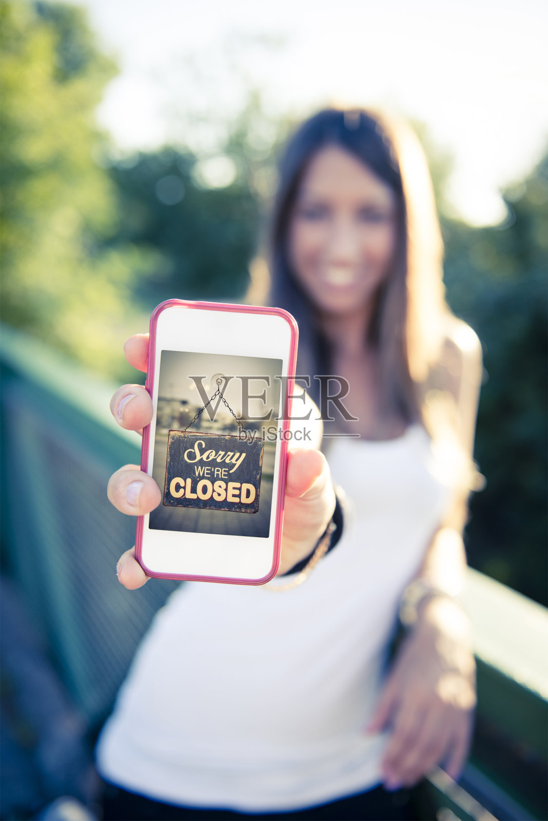 一个女人拿着智能手机，屏幕上显示着关闭的标识照片摄影图片