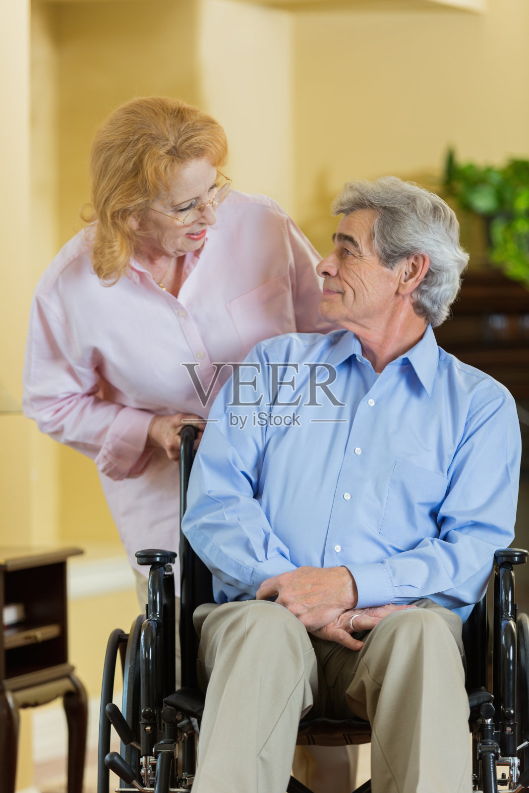 老年妇女在家中推着坐轮椅的丈夫照片摄影图片