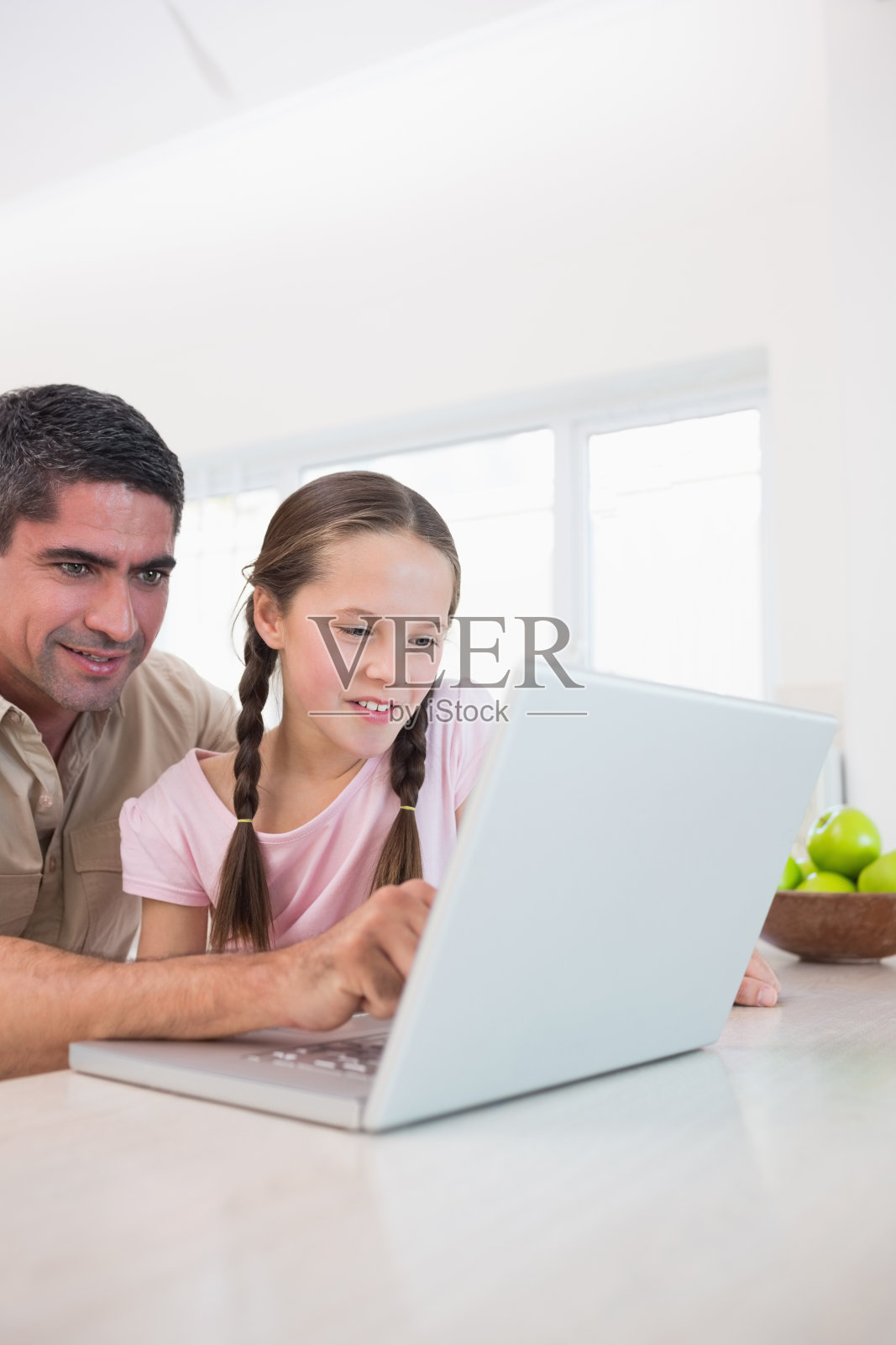 父亲和微笑的女儿在厨房使用笔记本电脑照片摄影图片