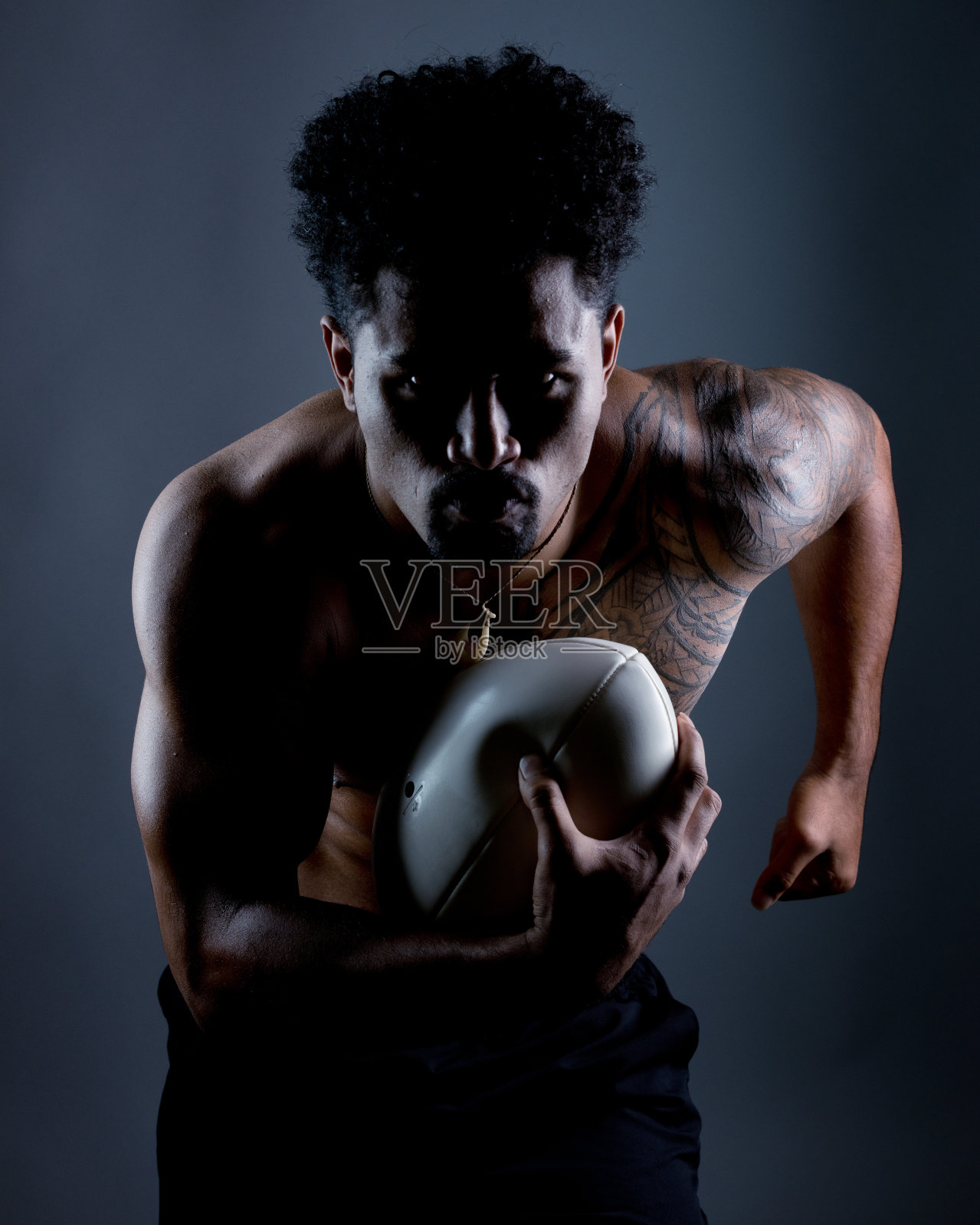 带着橄榄球跑的肌肉男照片摄影图片