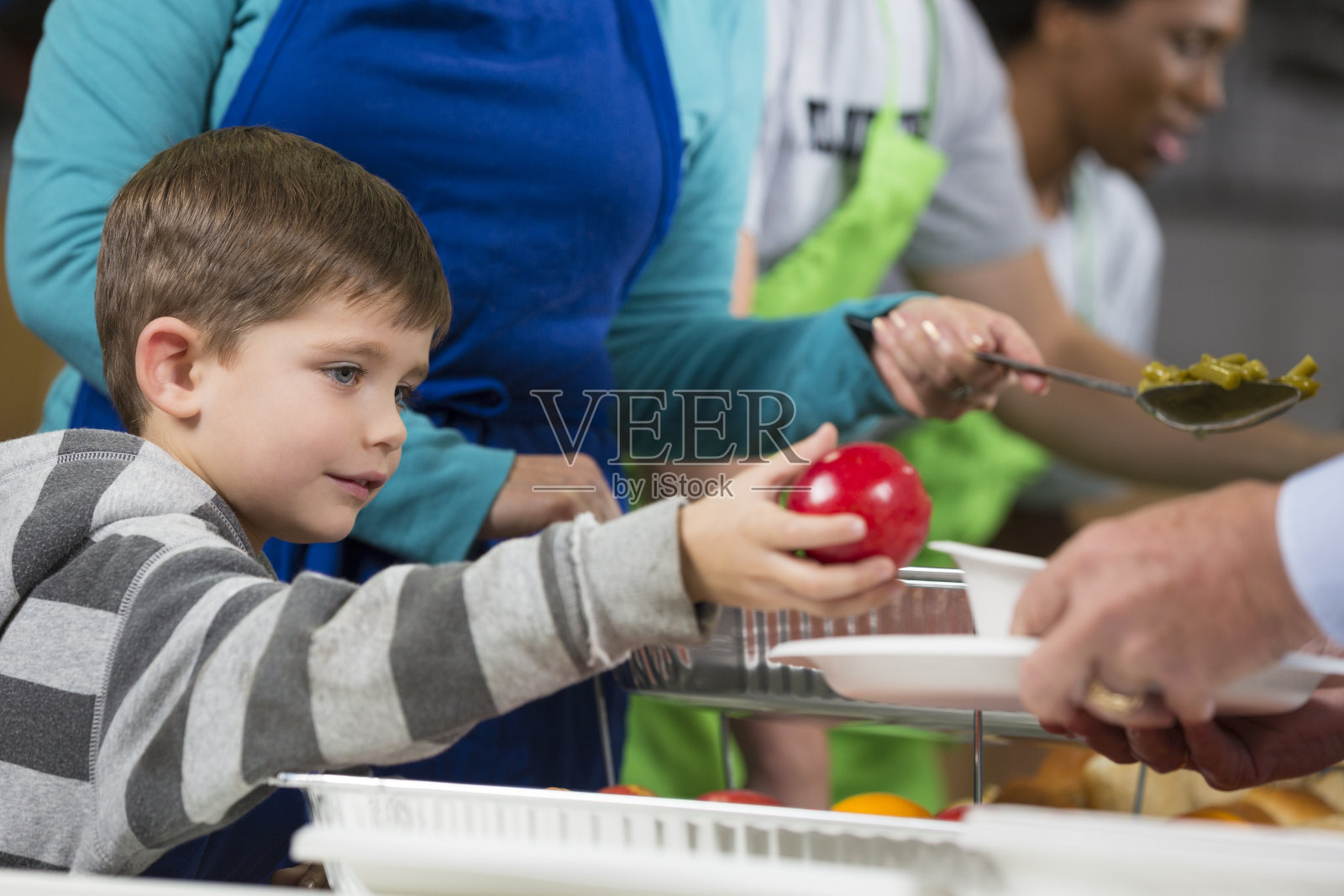 小男孩和祖父母一起在施粥处做义工照片摄影图片