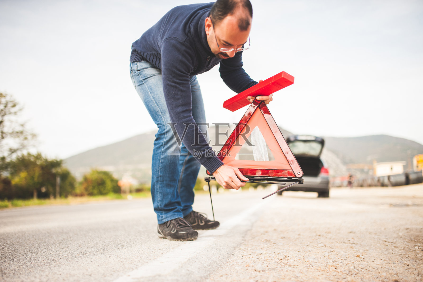 男子在道路上放置三角形警告标志照片摄影图片