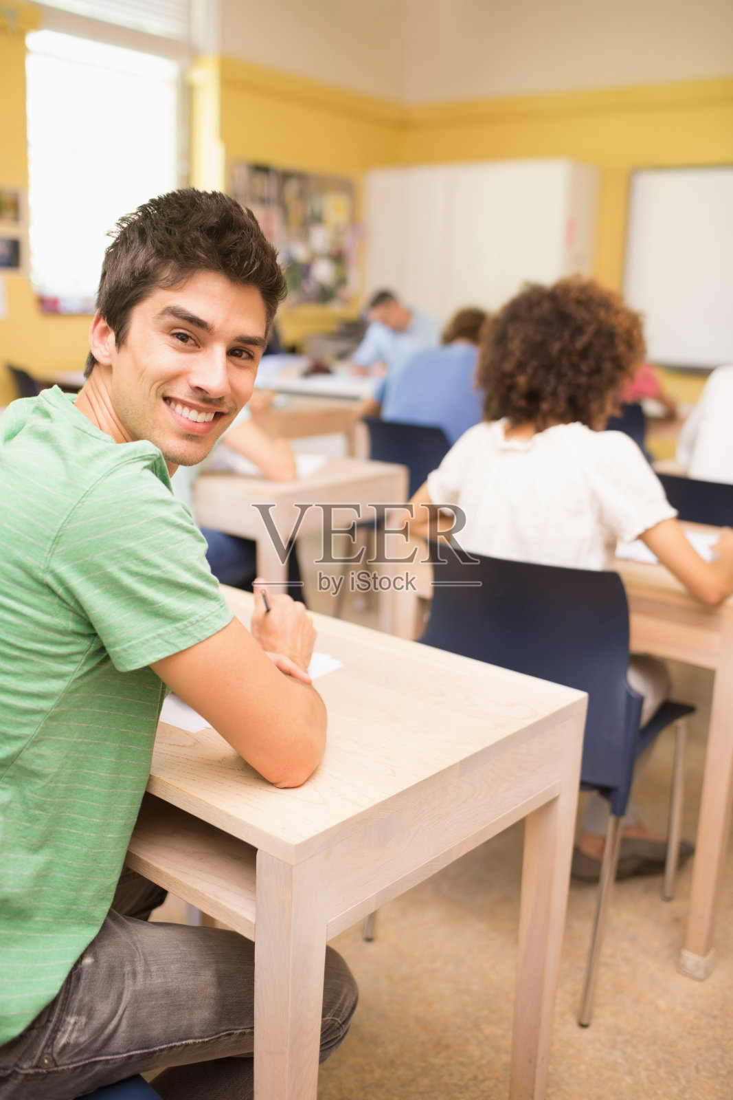 快乐的学生坐在课桌在教室里照片摄影图片