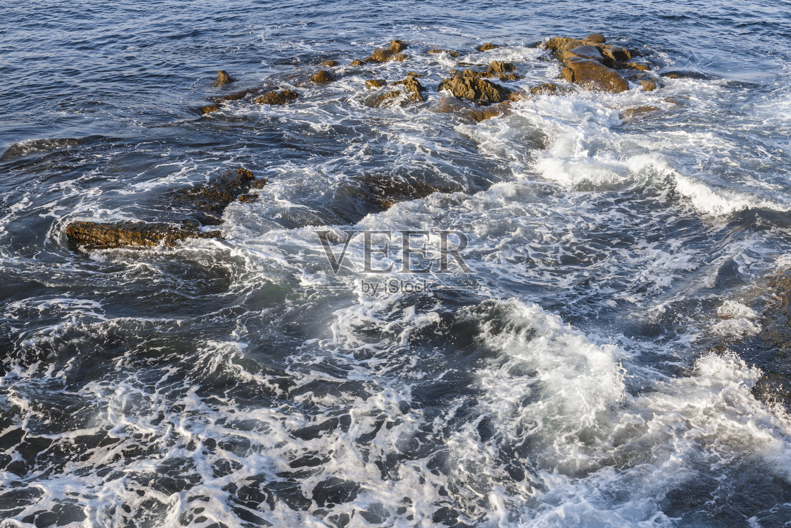 海浪撞击着淹没的岩石照片摄影图片