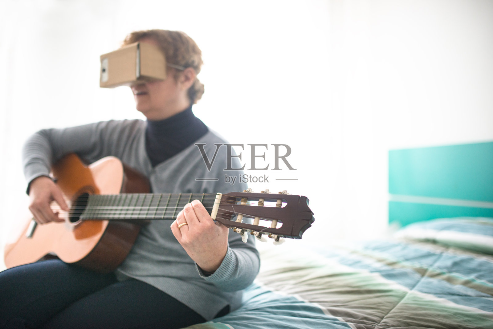 一个拿着吉他看虚拟现实设备模拟器的女人照片摄影图片