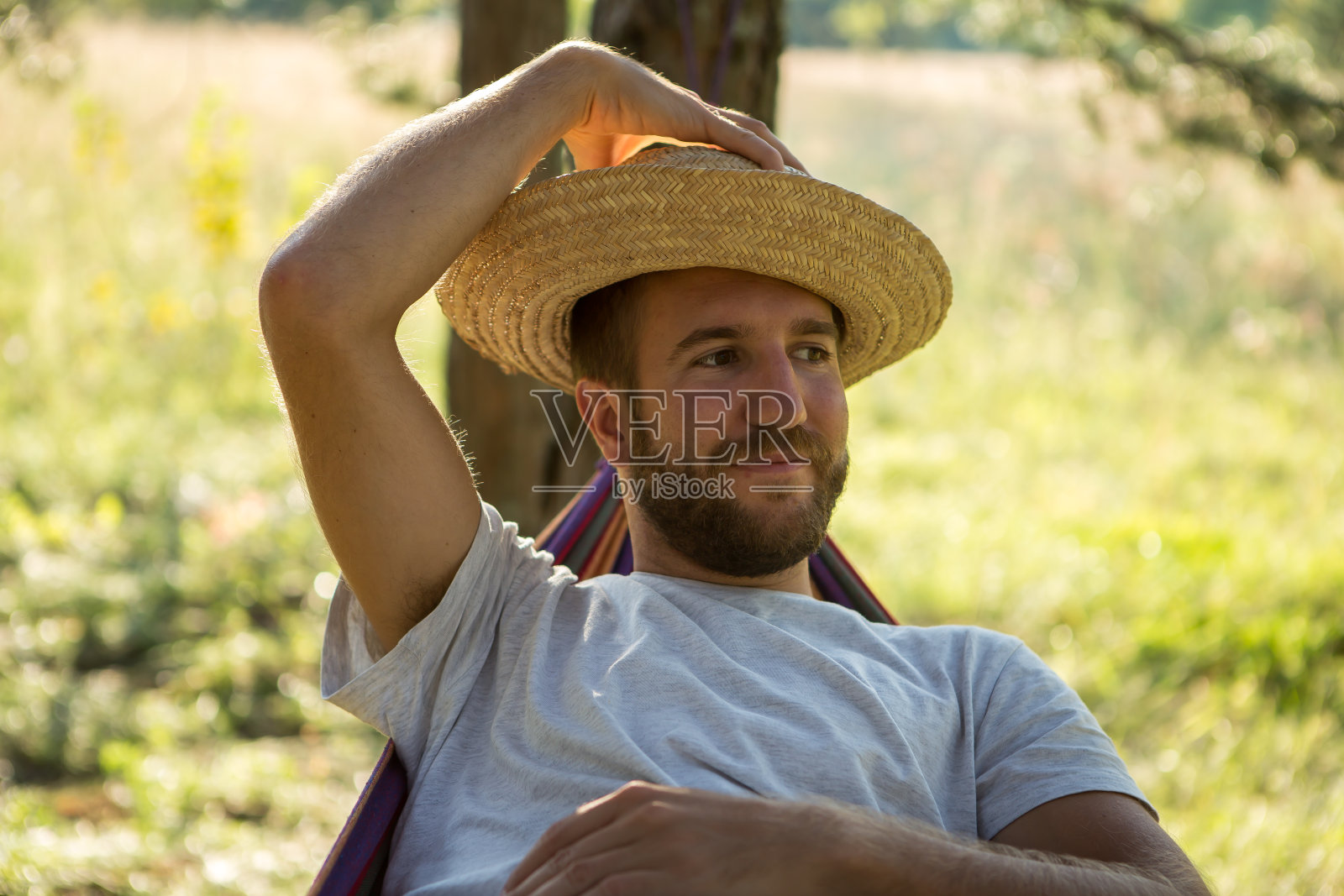 戴草帽在吊床上放松的年轻男人照片摄影图片