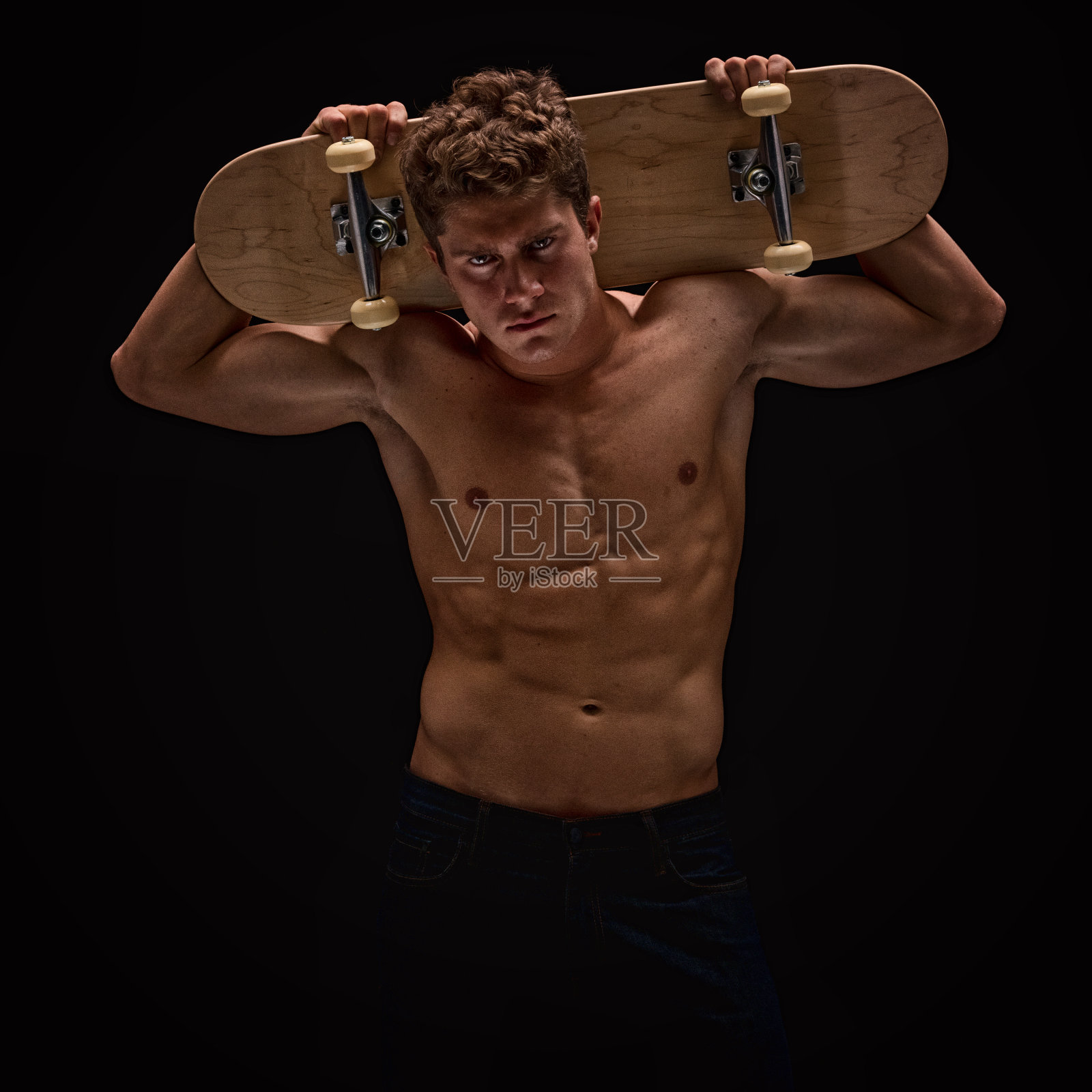 赤裸上身的肌肉男握着长板照片摄影图片