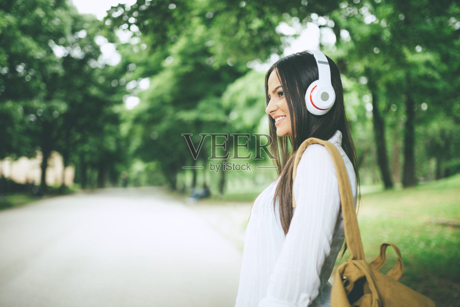 年轻漂亮的女学生在公园里听音乐照片摄影图片