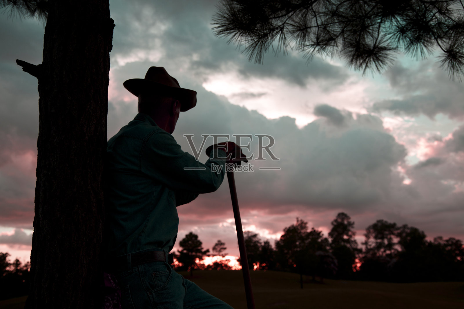 牧童:日落下暴雨后，俯瞰田野的农民剪影。照片摄影图片