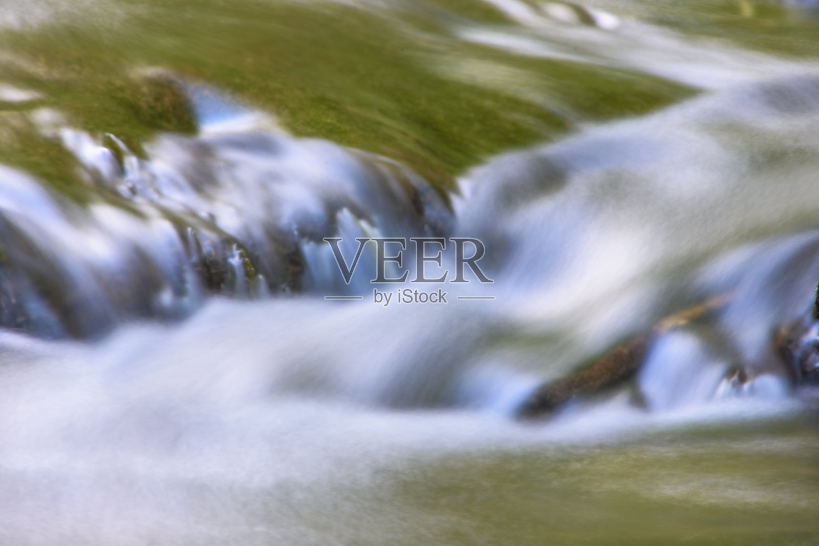 流过长满苔藓的岩石的小溪照片摄影图片