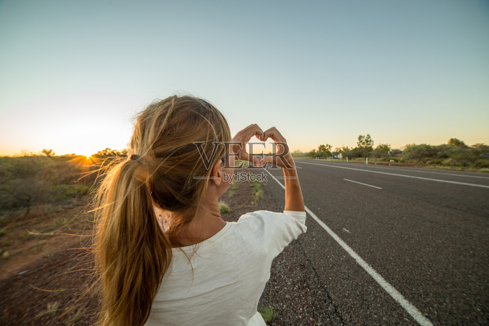 白人女性站在路边，做心形指架照片摄影图片