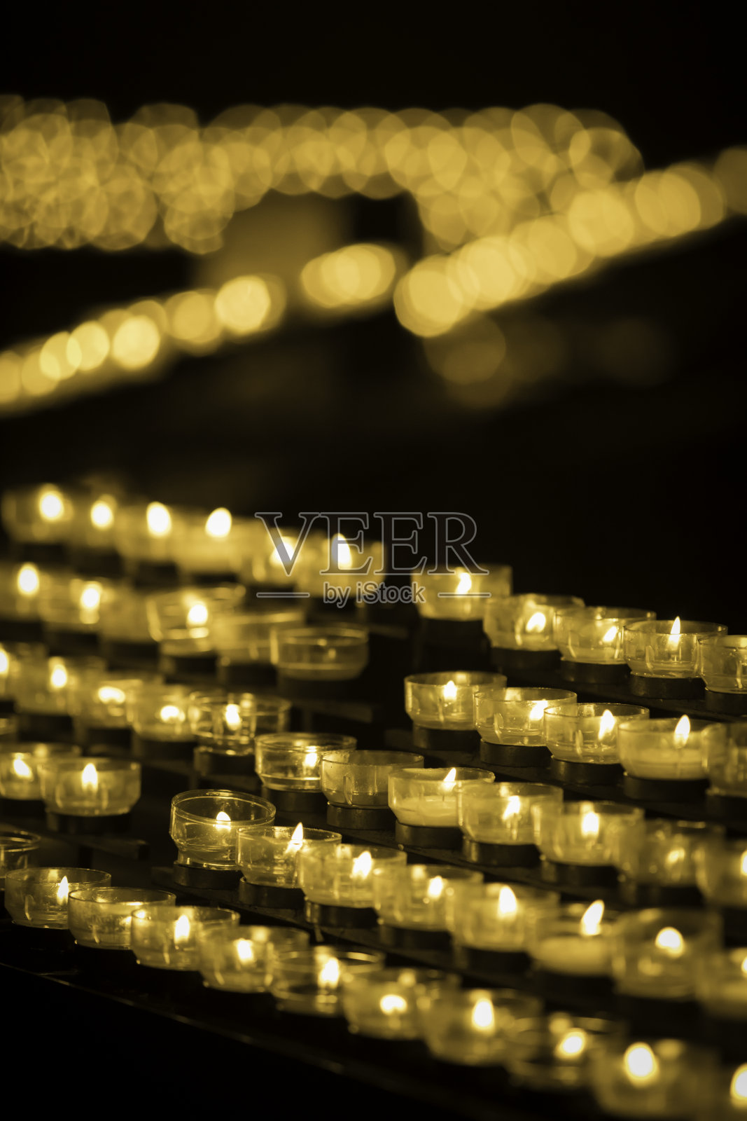 在黑暗的教堂里，成排的蜡烛燃烧着照片摄影图片