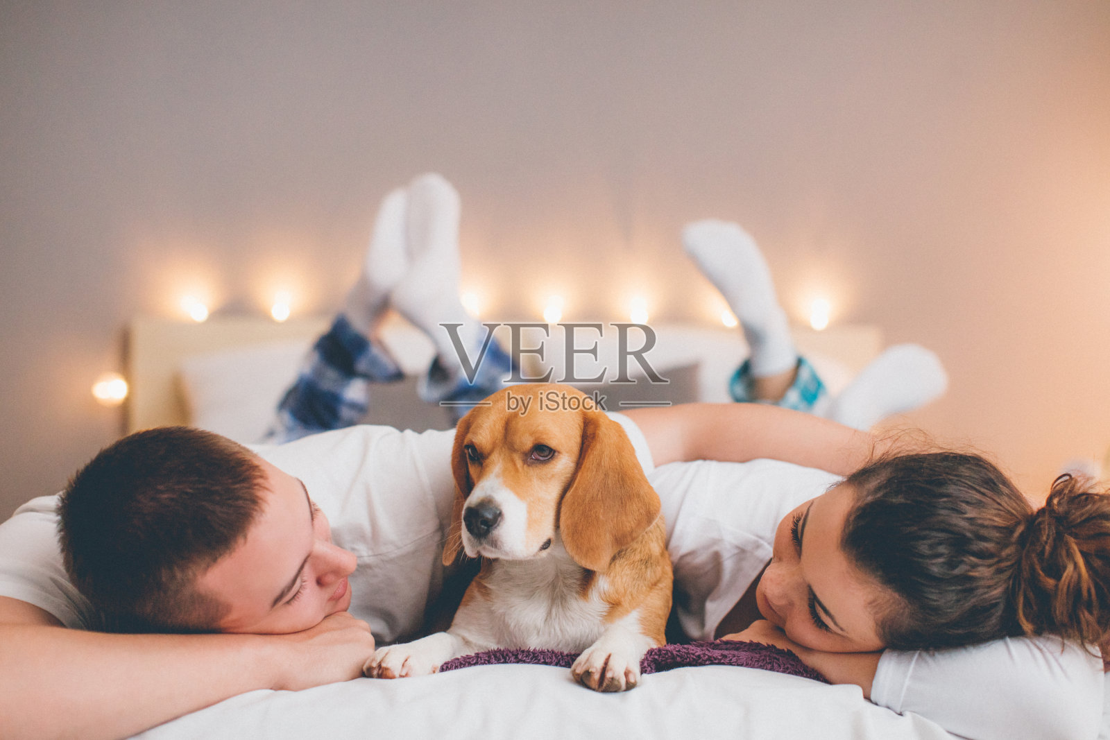 一对年轻夫妇和她的宠物狗在床上休息照片摄影图片
