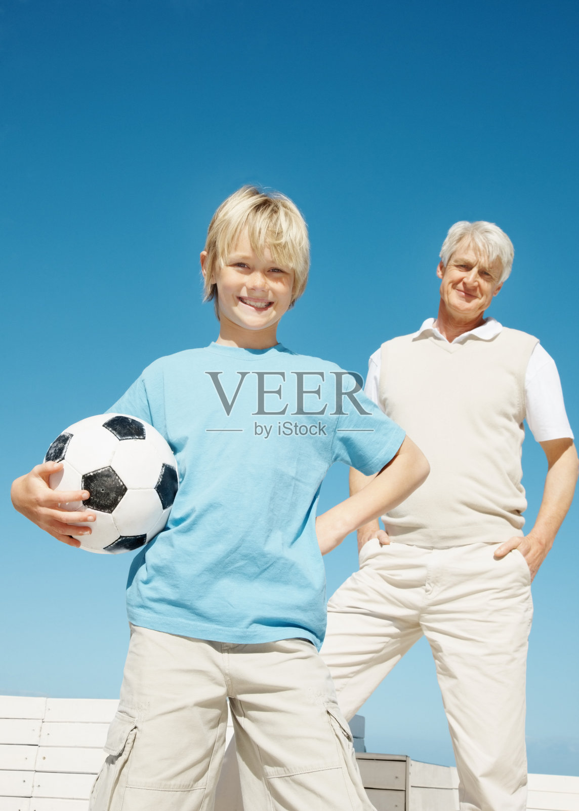 一个男孩拿着一个足球，后面是他的爷爷照片摄影图片