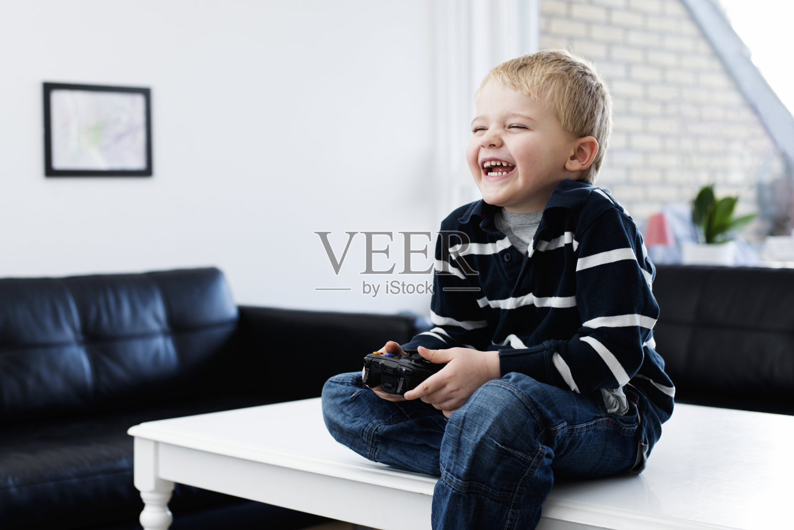 男孩在玩电子游戏的时候笑了照片摄影图片