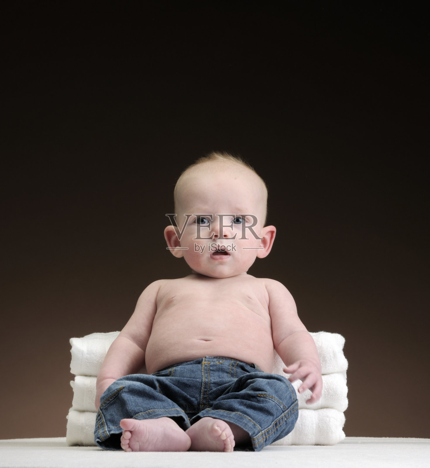 小男孩靠着白色毛巾坐着照片摄影图片