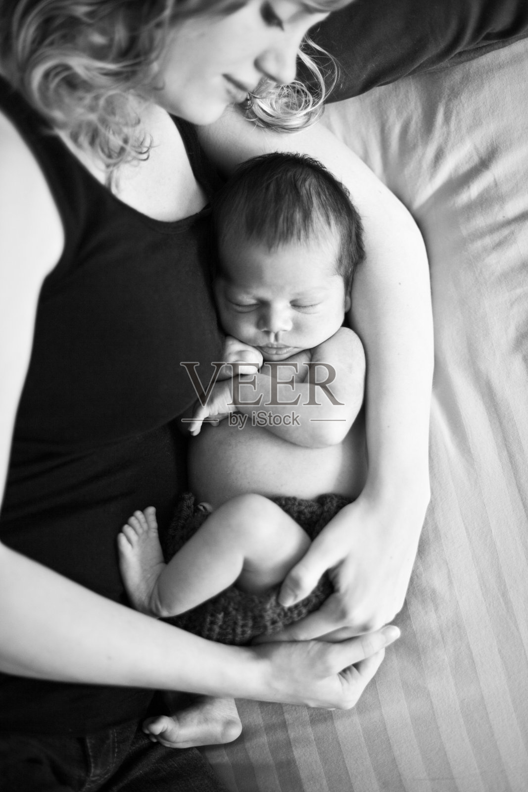 新生儿在母亲的怀里安静地睡觉，黑白相间照片摄影图片