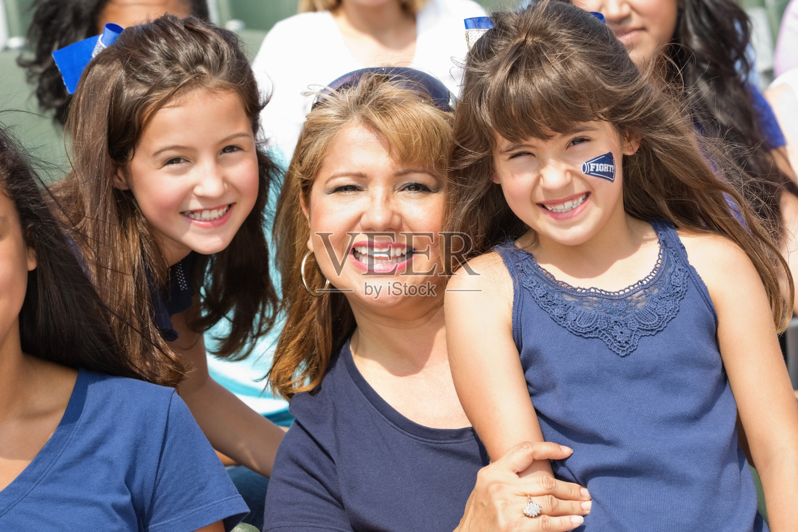 妈妈带着两个年幼的女儿在体育场参加体育赛事照片摄影图片