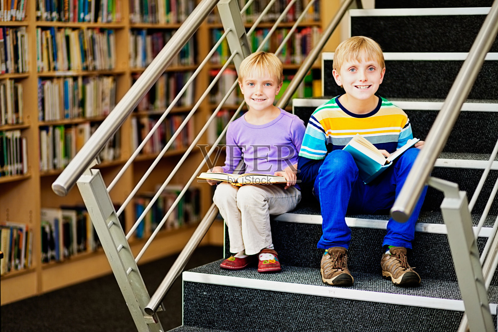 微笑的金发兄弟姐妹喜欢在图书馆的台阶上读书照片摄影图片