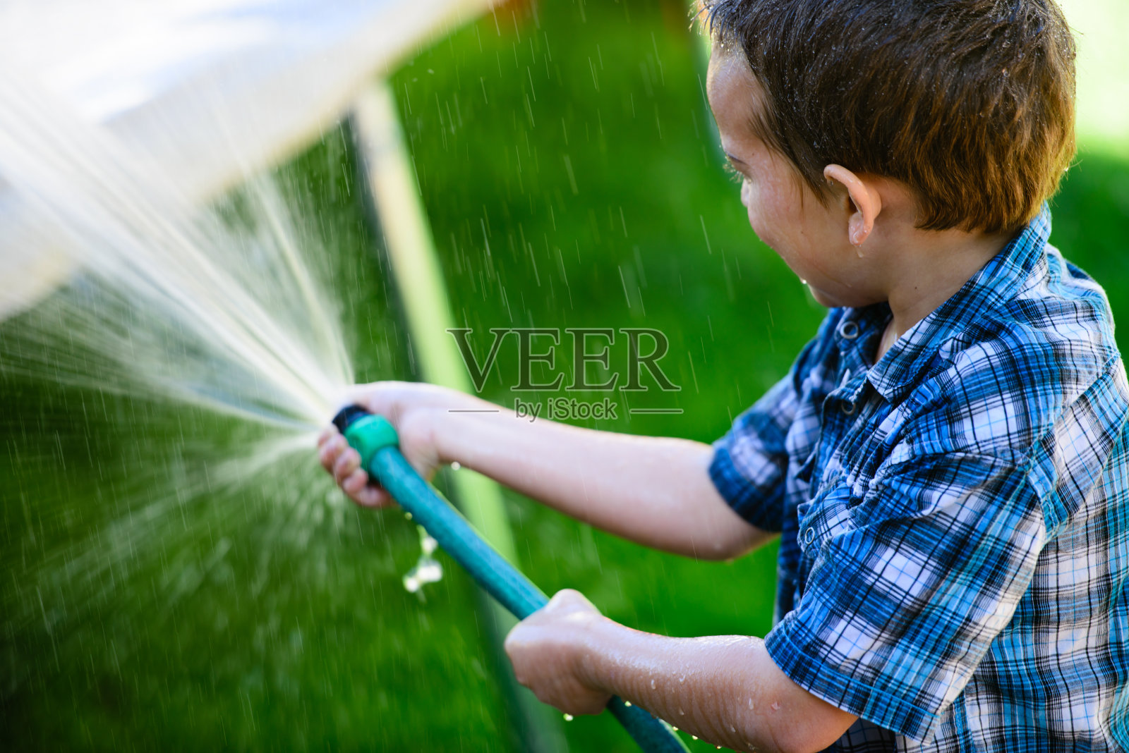 玩花园软管的男孩照片摄影图片