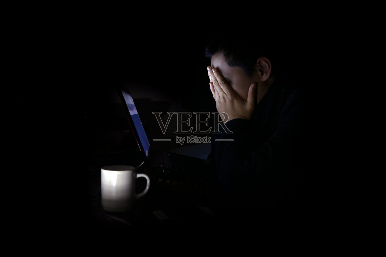 一个疲惫的年轻人晚上在玩笔记本电脑照片摄影图片