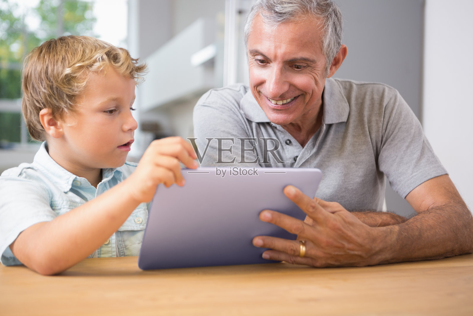 微笑的爷爷和他的孙子触摸着平板电脑照片摄影图片