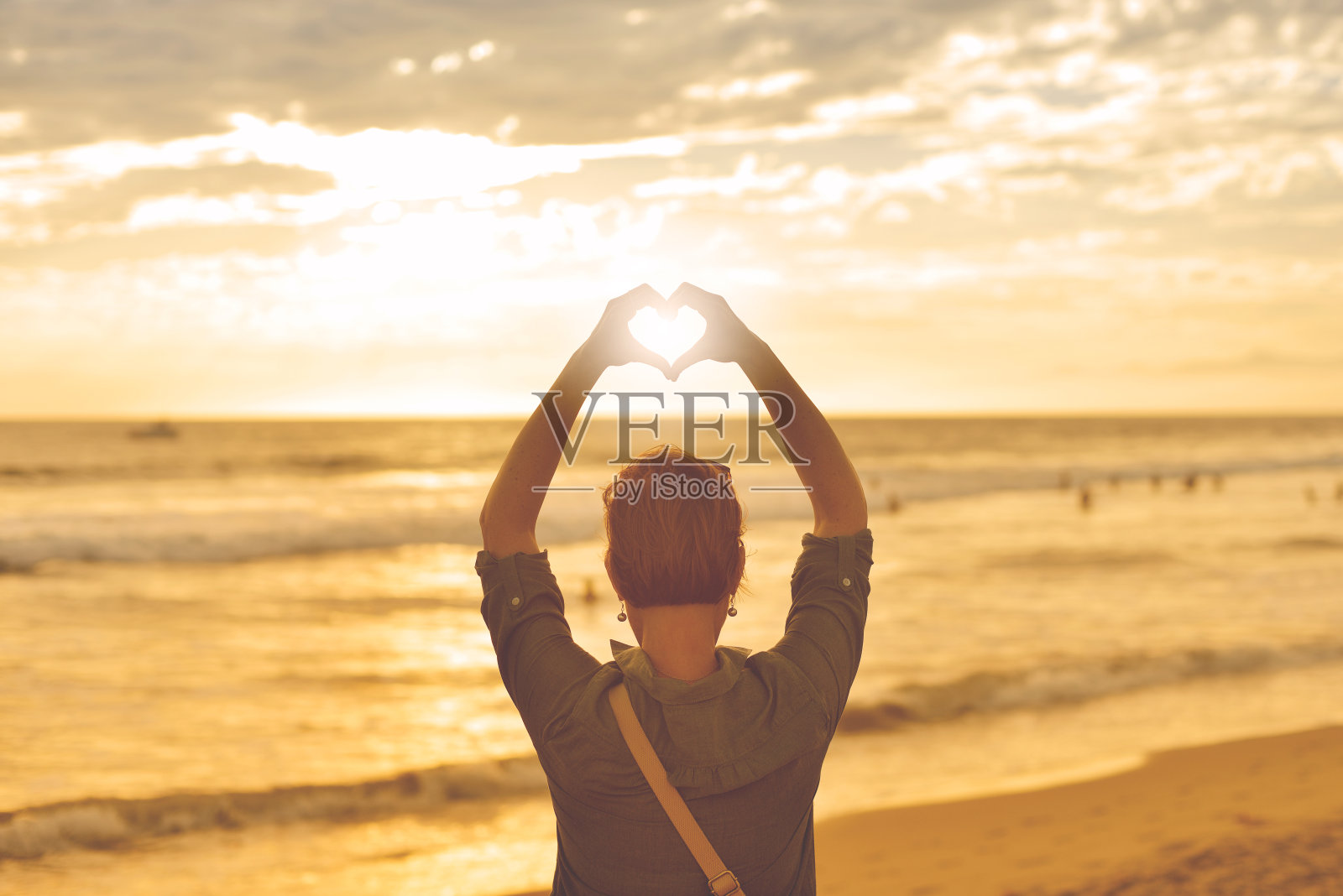 一个人站在沙滩上用手做一个心形照片摄影图片