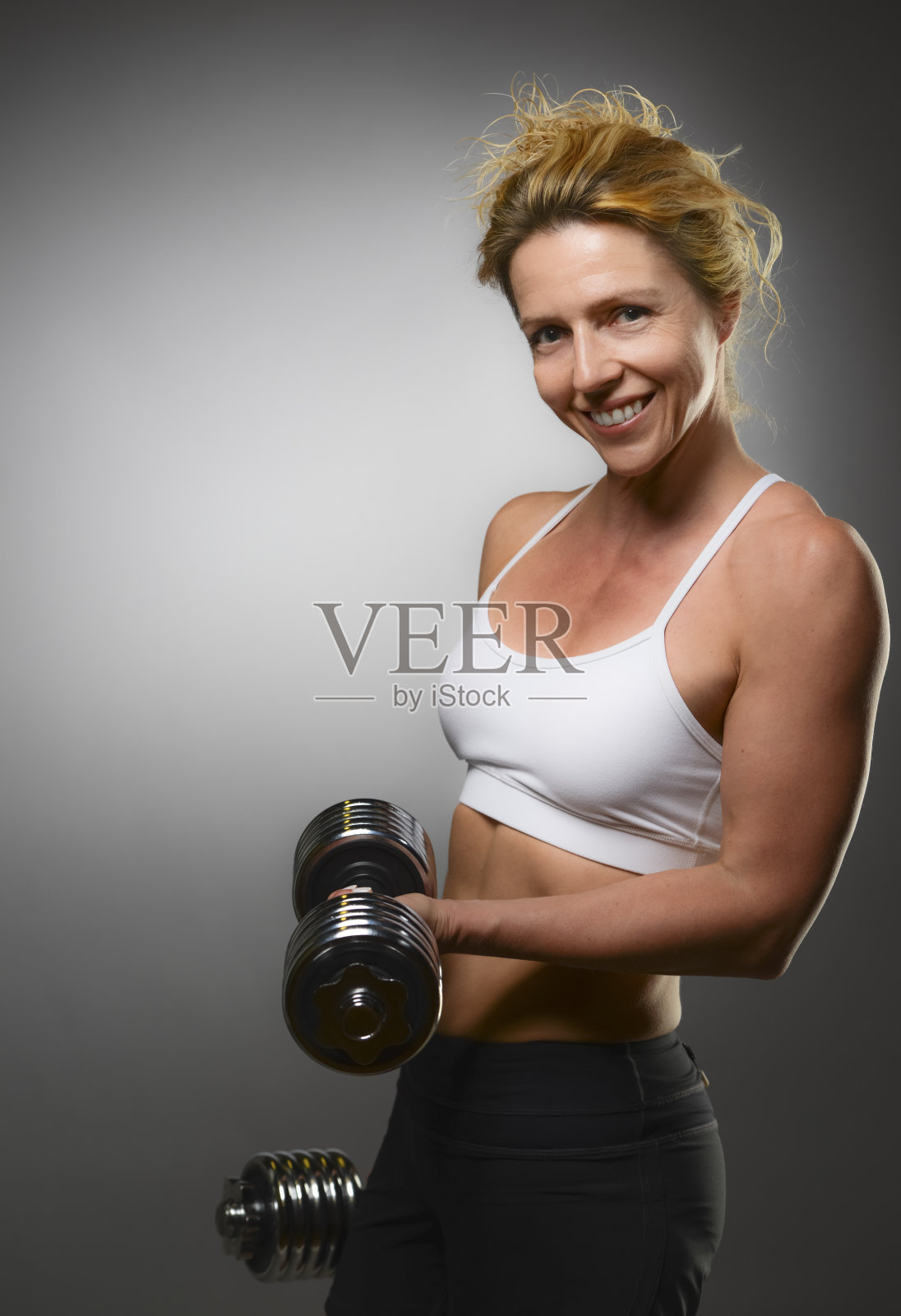 快乐的40岁女孩摆着哑铃照片摄影图片