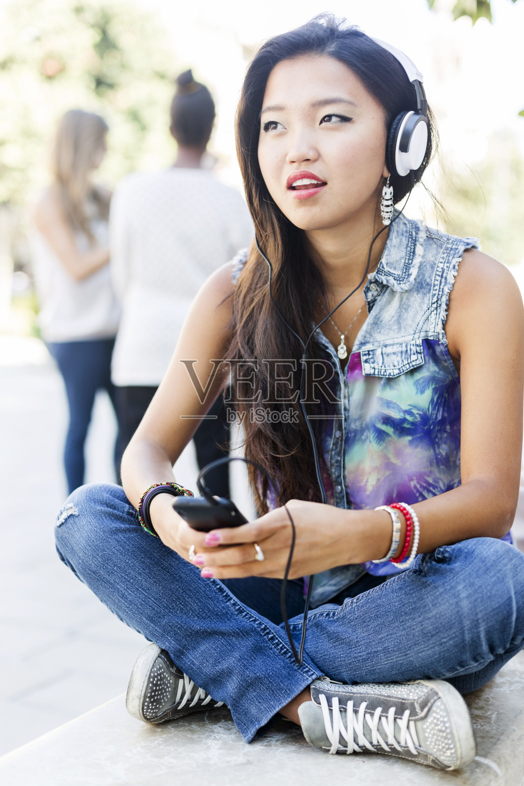 年轻的亚洲女性正在用智能手机听音乐照片摄影图片