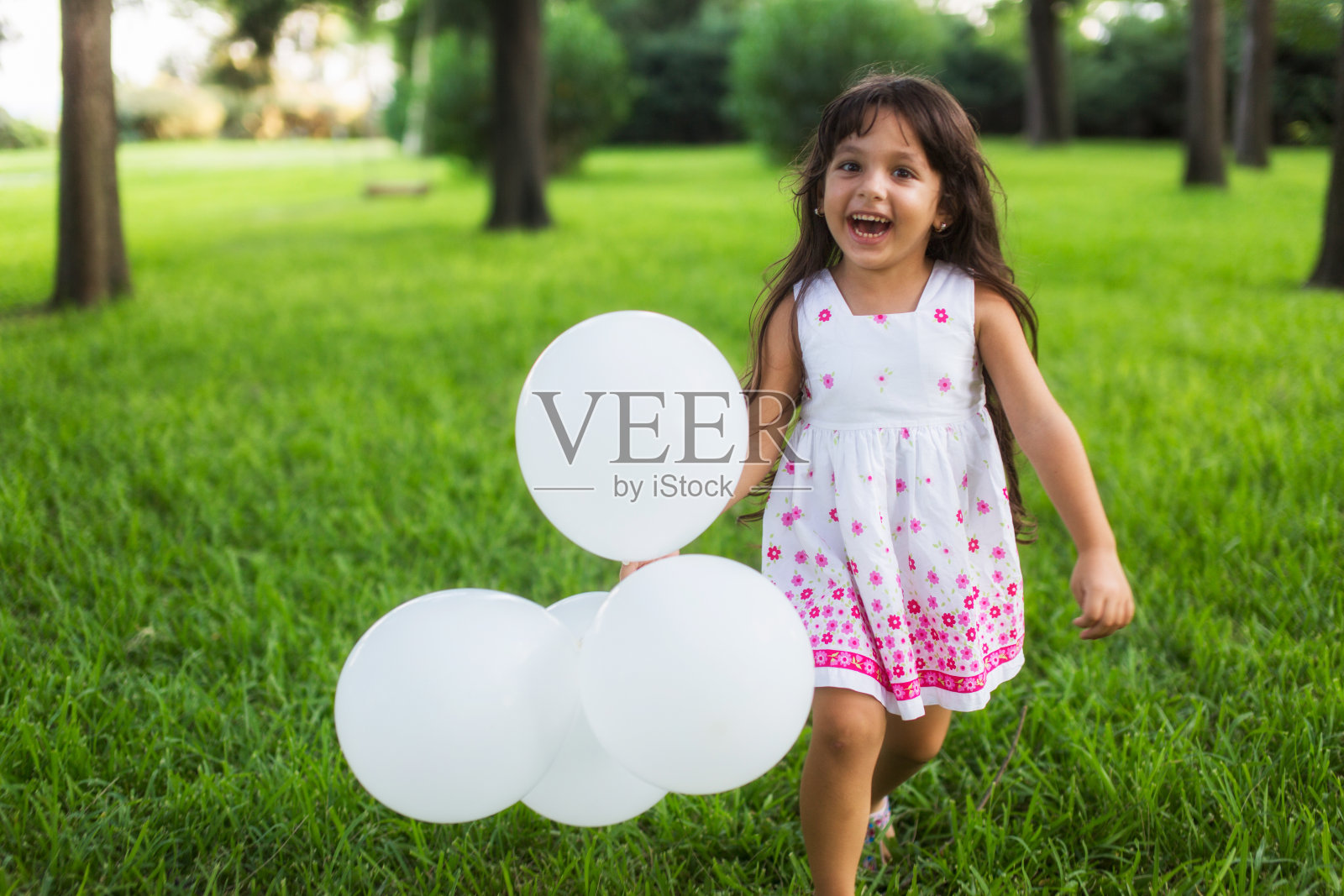 小女孩拿着白气球在公园里奔跑照片摄影图片