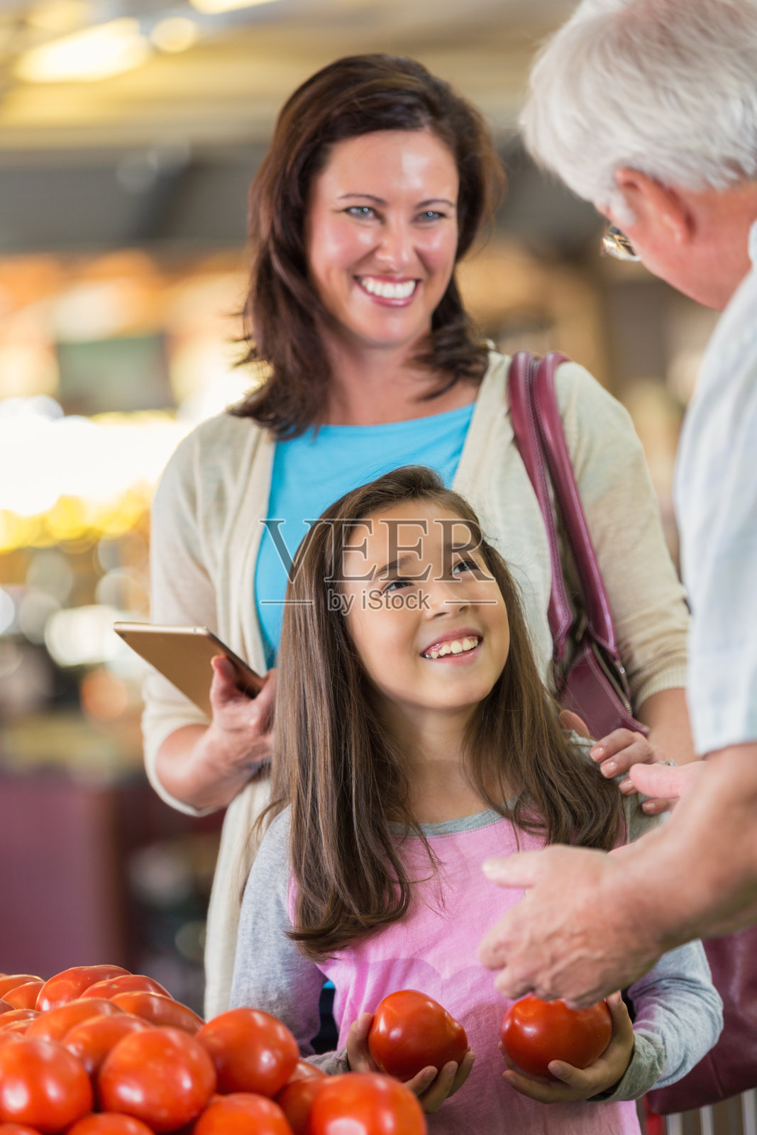 妈妈和女儿与杂货店的农产品经理交谈照片摄影图片