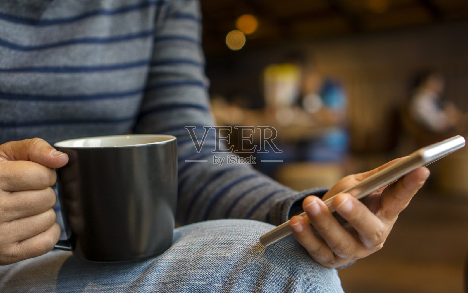 女孩一边喝咖啡一边看手机照片摄影图片