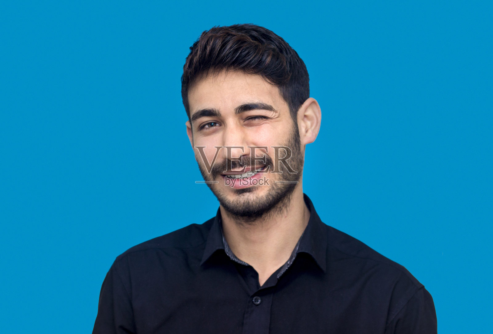 一个眨眼的年轻人被孤立在蓝色的肖像照片摄影图片