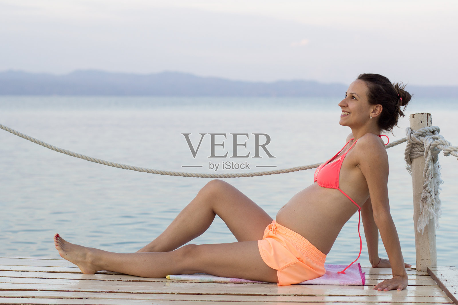 坐在湖边码头上的女人照片摄影图片