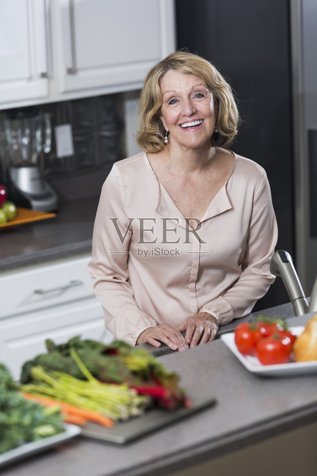 厨房里的老妇人，柜台上放着蔬菜照片摄影图片