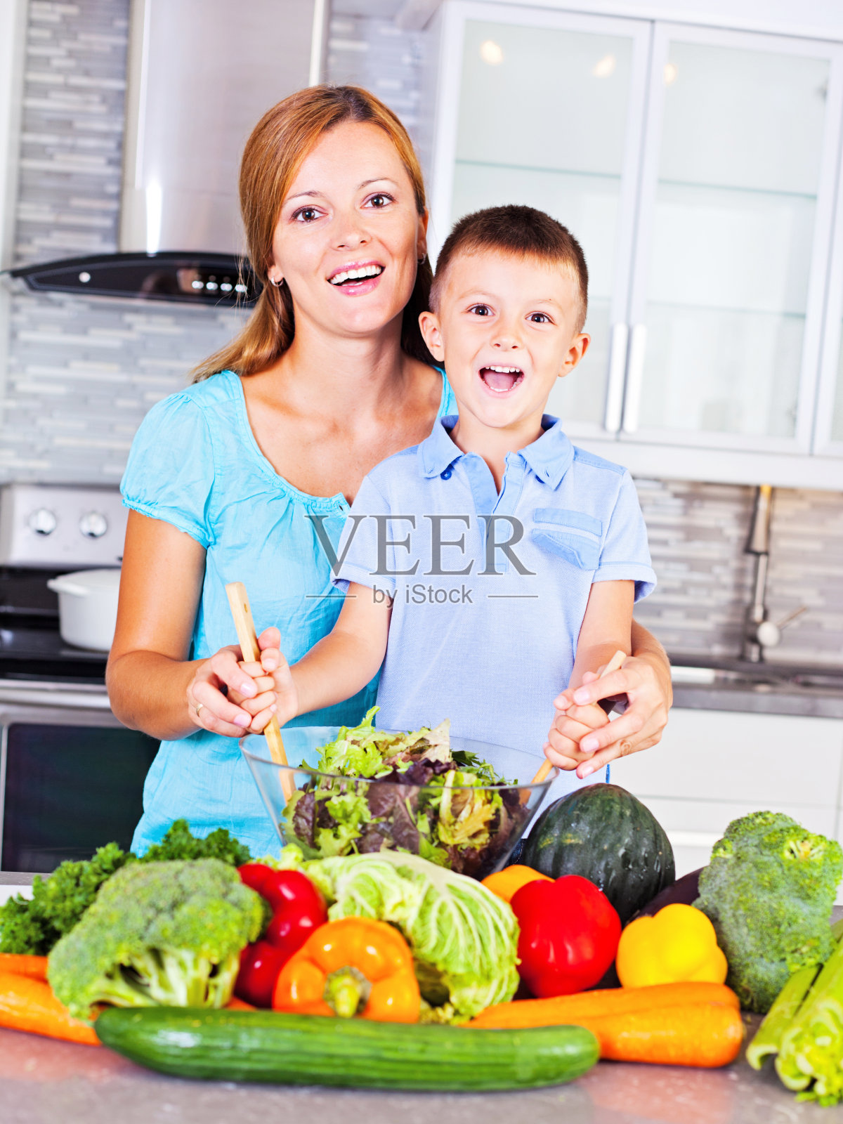 母亲和儿子在蔬菜周围做沙拉照片摄影图片