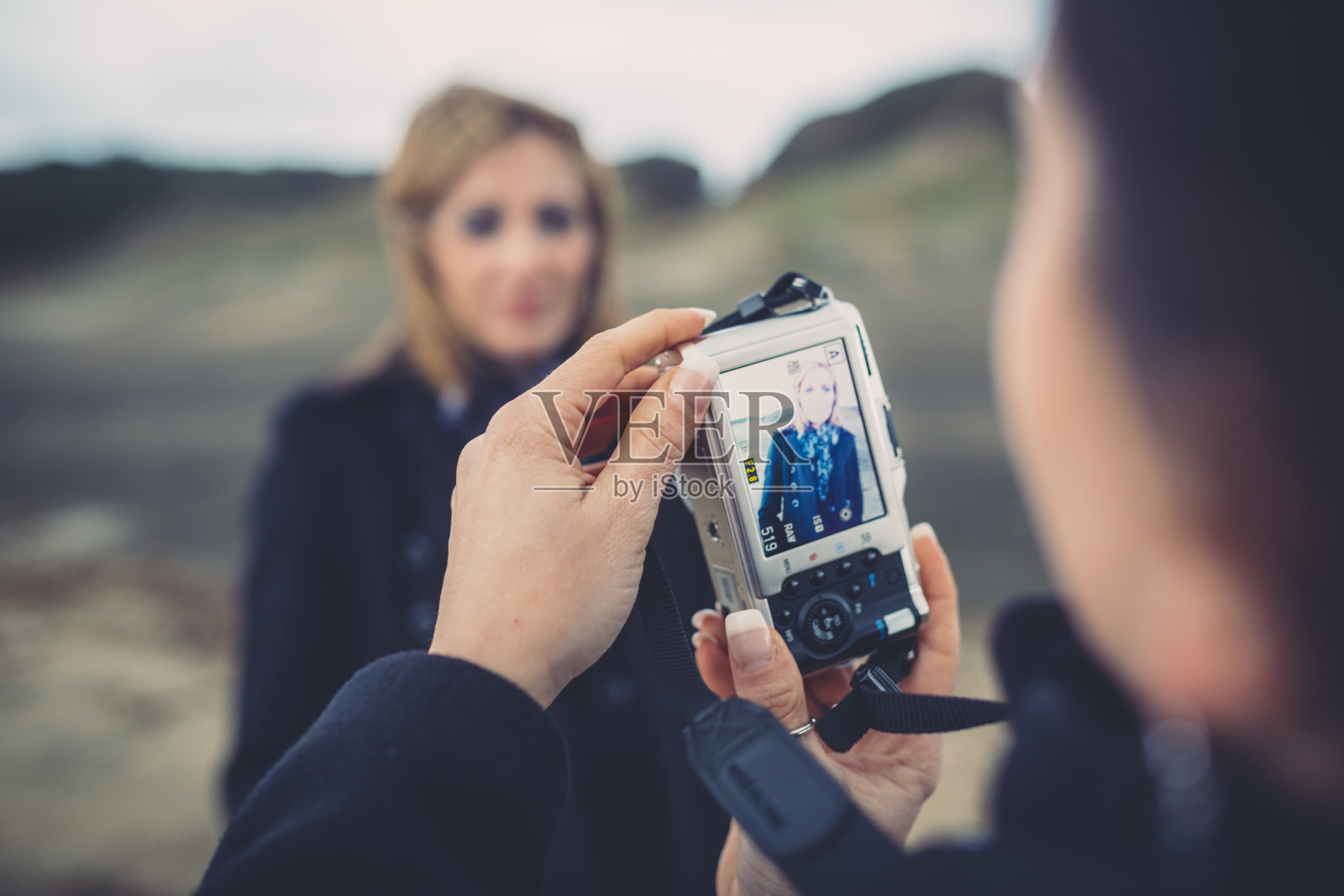 一个女人正在用数码相机给她的朋友拍照照片摄影图片