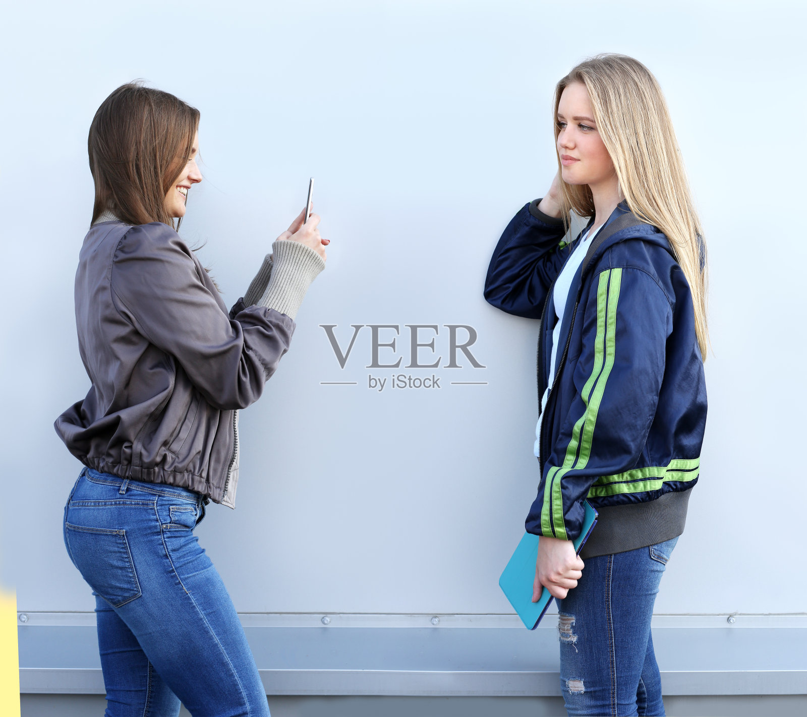 两个迷人的女孩在笑。使用智能手机照片摄影图片