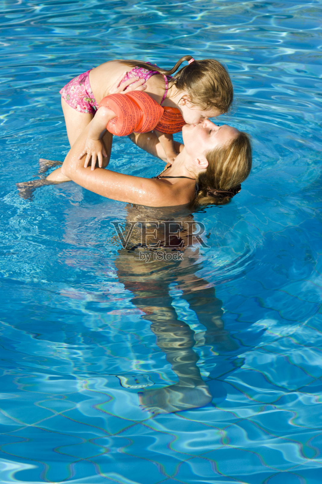 妈妈和小女儿在泳池里接吻照片摄影图片
